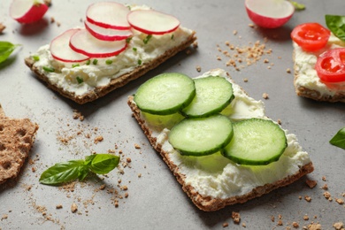 Photo of Tasty snacks with cream cheese and vegetables on gray table