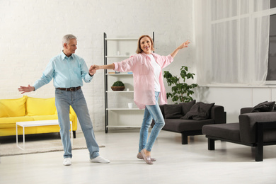 Happy senior couple dancing together in living room