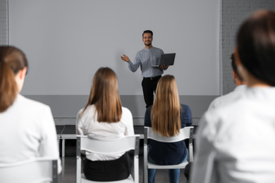 Photo of Male business trainer with laptop giving lecture in conference room with projection screen