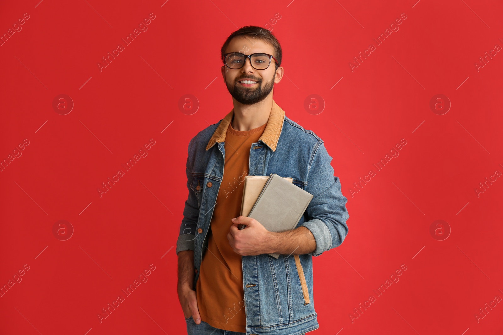 Photo of Happy student with books on red background