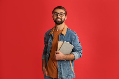 Photo of Happy student with books on red background