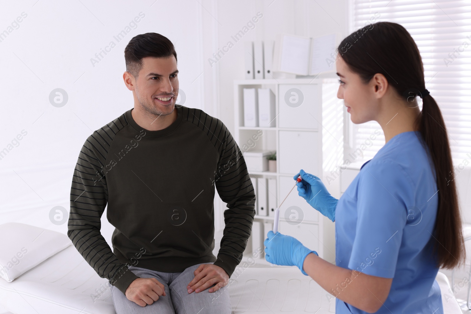 Photo of Doctor taking sample for STD testing from man in clinic