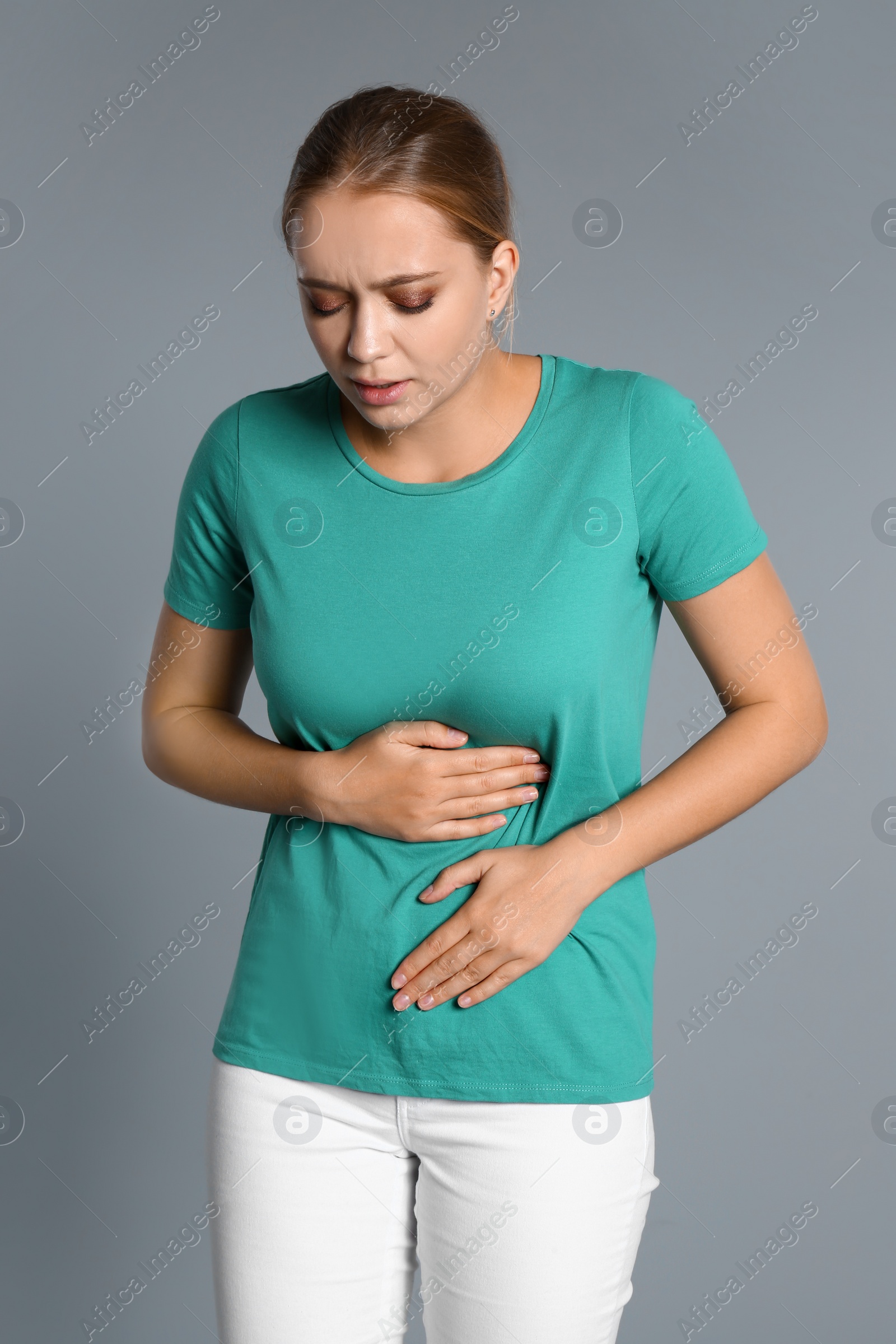 Photo of Woman suffering from stomach pain on grey background