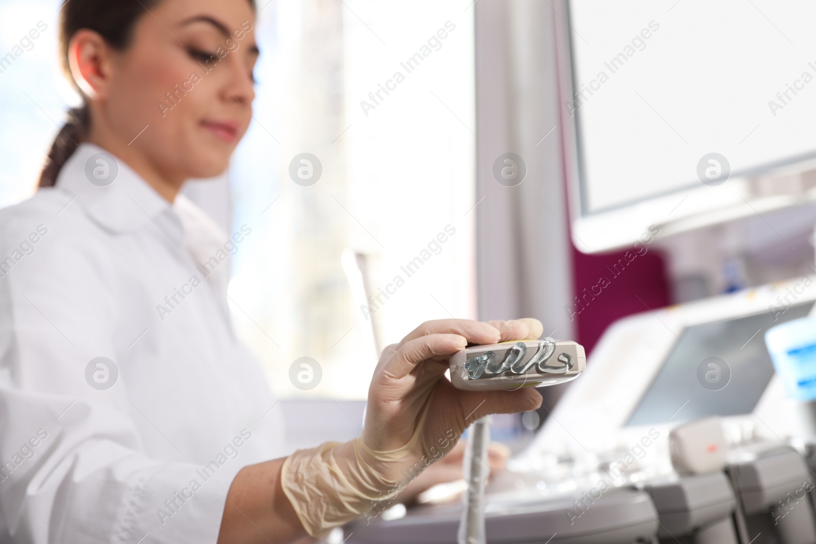 Photo of Sonographer holding ultrasound machine probe with gel in clinic