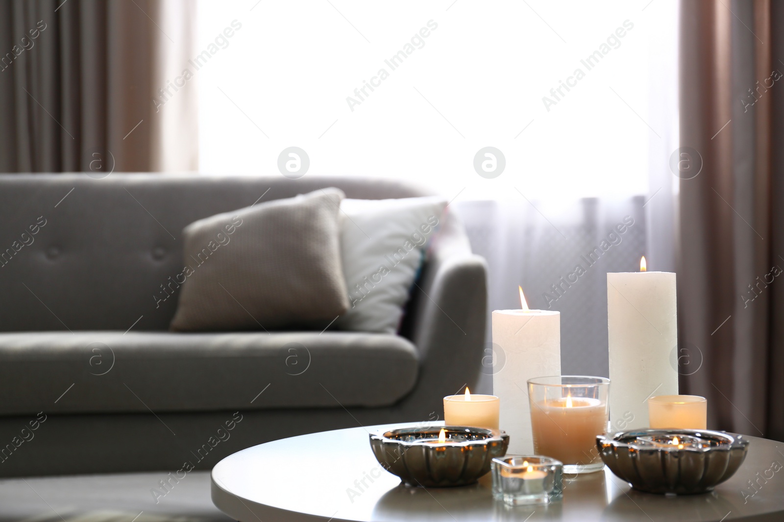 Photo of Burning decorative candles on table in room