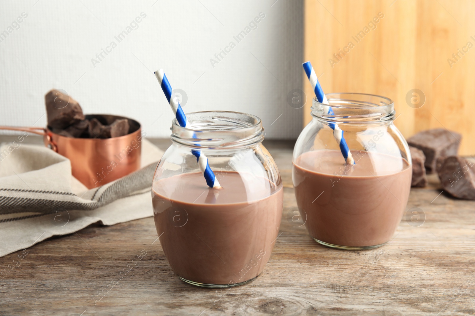 Photo of Jars with tasty chocolate milk on wooden table. Dairy drink