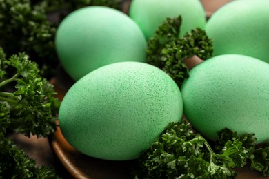 Turquoise Easter eggs painted with natural dye and curly parsley on table, closeup