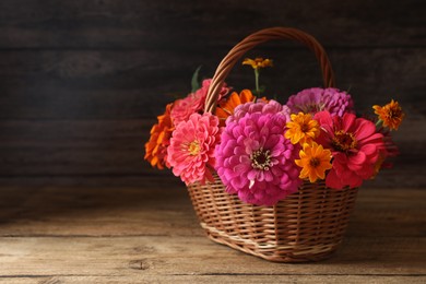 Photo of Beautiful wild flowers in wicker basket on wooden table. Space for text