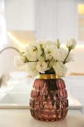 Photo of Bouquet of beautiful flowers on countertop in kitchen. Interior design