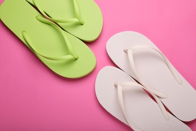 Photo of Stylish white and light green flip flops on pink background, flat lay
