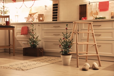 Photo of Small Christmas trees and festive decor in kitchen