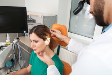 Photo of Professional otolaryngologist examining woman in clinic. Hearing disorder