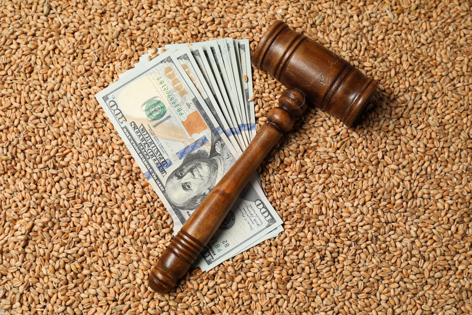 Photo of Dollar banknotes and wooden gavel on wheat grains, top view. Agricultural business