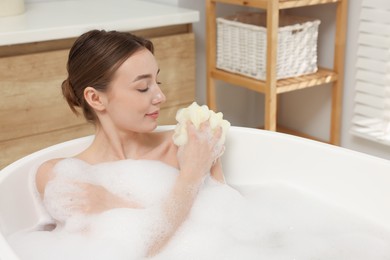 Woman taking bath with shower gel in bathroom