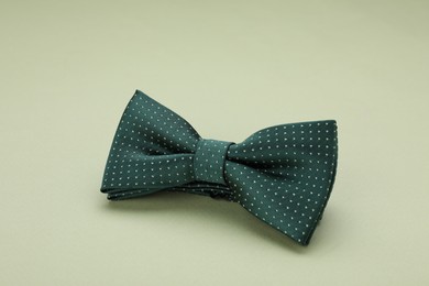 Photo of Stylish bow tie with polka dot pattern on pale green background