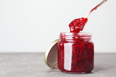 Photo of Sweet raspberry jam on grey table. Space for text