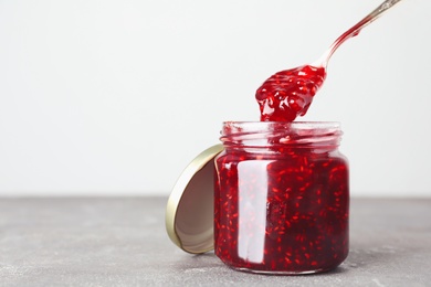 Sweet raspberry jam on grey table. Space for text