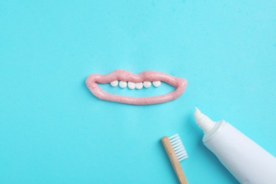 Photo of Mouth with teeth made of paste, tube and brush on color background, flat lay