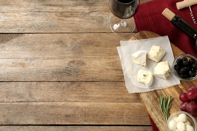 Photo of Flat lay composition with red wine and snacks on wooden table, space for text