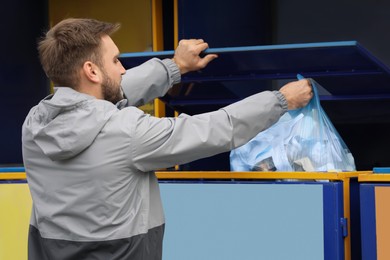 Photo of Man throwing garbage into bin at recycling point outdoors