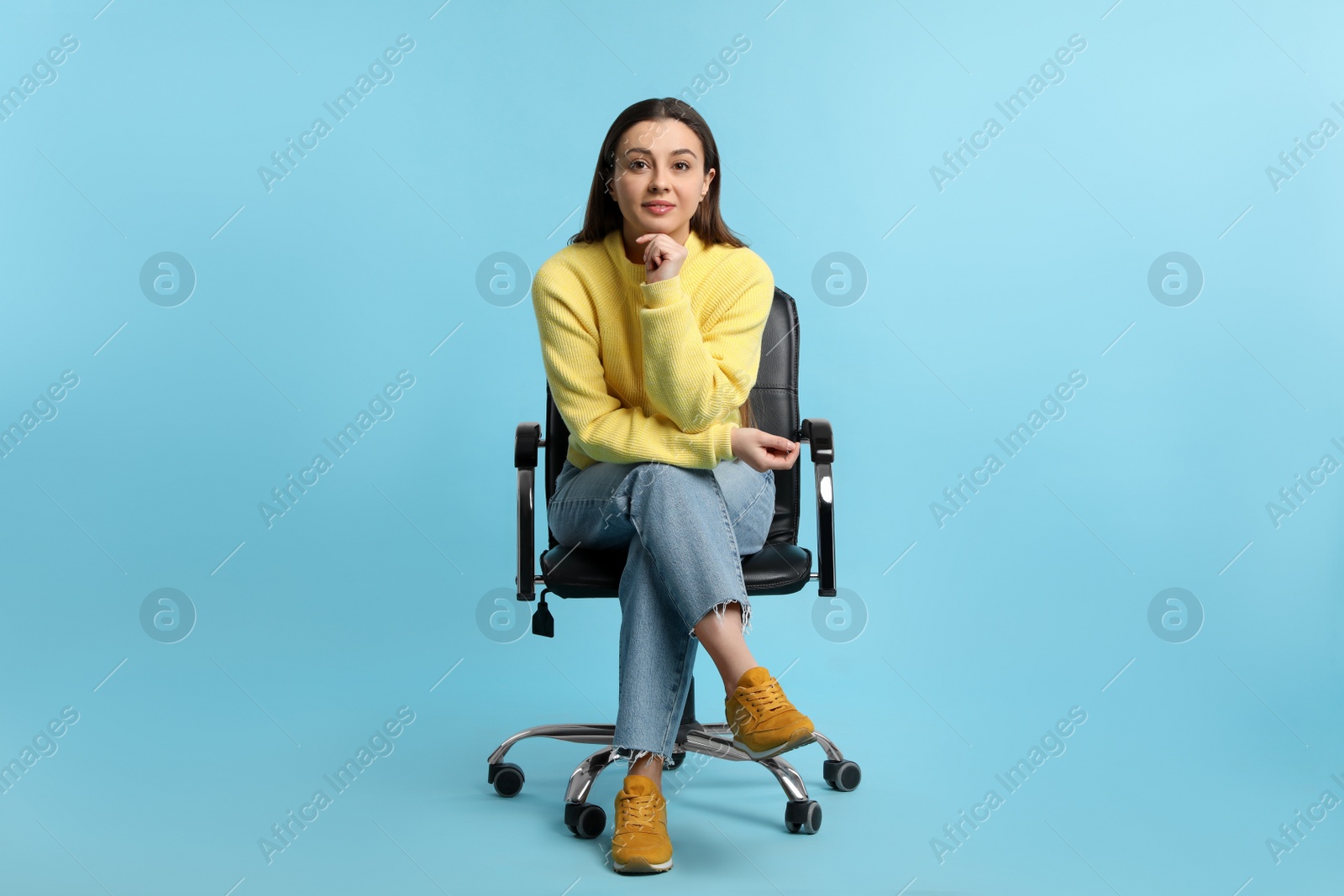 Photo of Young woman sitting in comfortable office chair on turquoise background