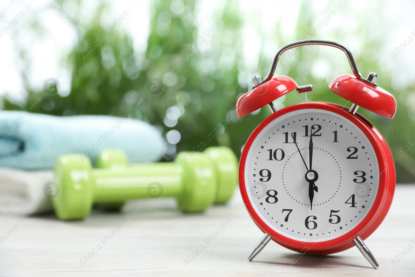 Photo of Alarm clock on white wooden table outdoors, space for text. Morning exercise