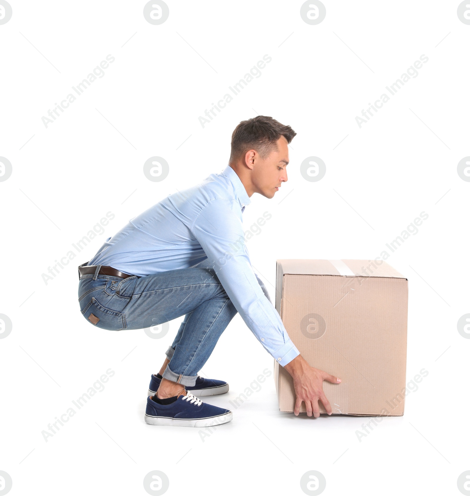 Photo of Full length portrait of young man lifting heavy cardboard box on white background. Posture concept