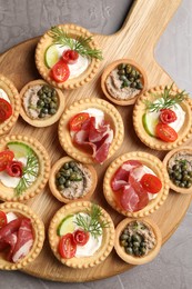 Delicious canapes with jamon, pate and dry smoked sausages on grey textured table, top view