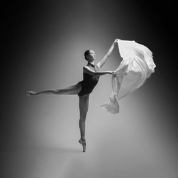 Image of Graceful young ballerina practicing dance moves with veil. Black and white effect