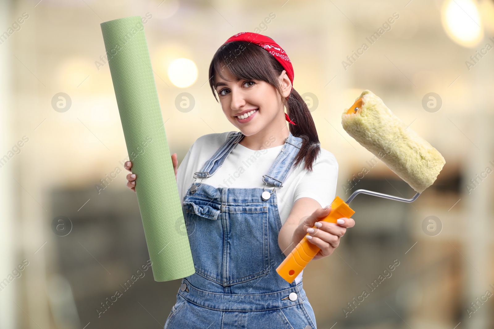 Image of Woman with wallpaper roll and roller on blurred background