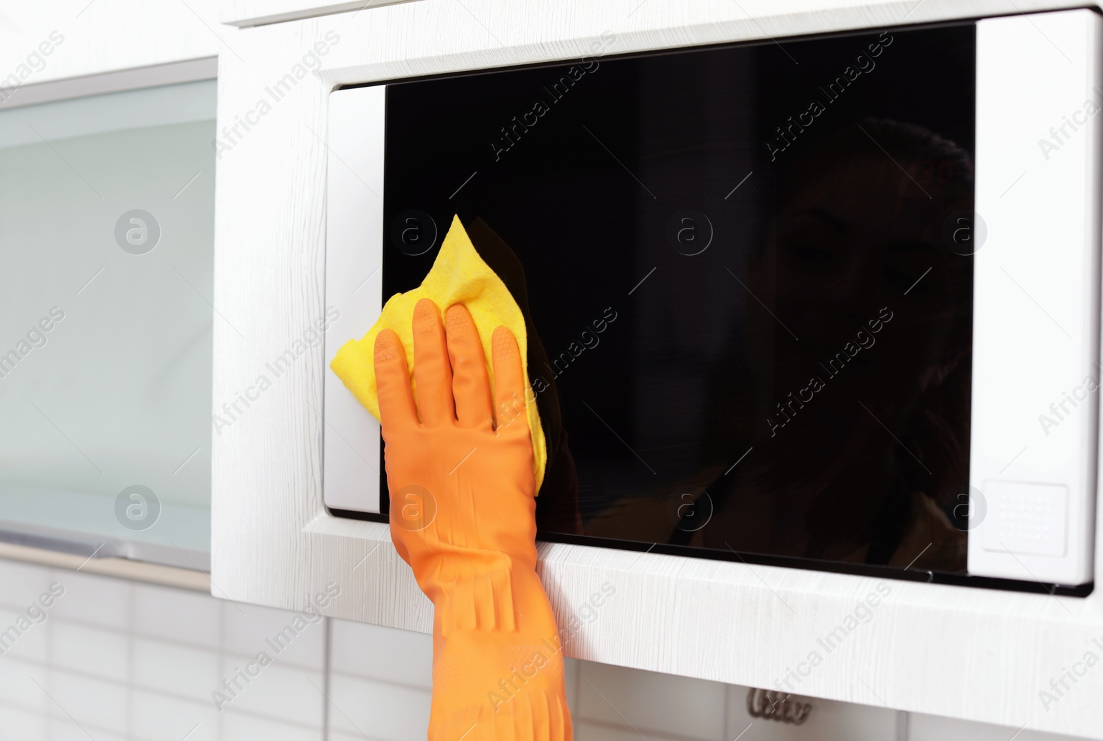 Photo of Woman cleaning oven with rag in kitchen, closeup