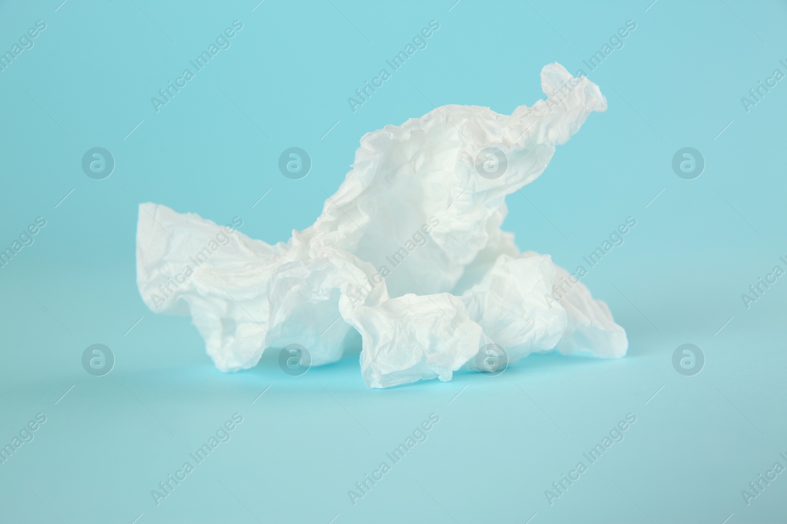 Photo of Used paper tissue on light blue background, closeup