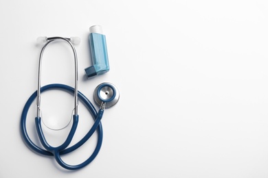 Photo of Asthma inhaler, stethoscope and space for text on white background, top view
