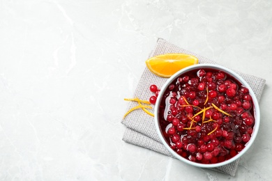 Fresh cranberry sauce and slice of orange on light marble table, flat lay. Space for text