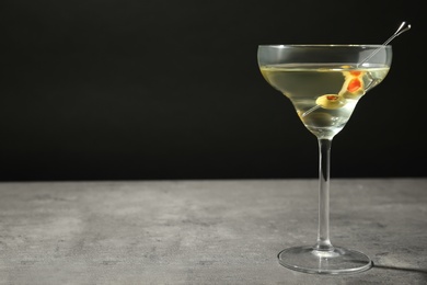 Photo of Glass of Classic Dry Martini with olives on grey table against black background. Space for text