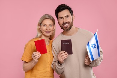 Photo of Immigration. Happy couple with passports and flag of Israel on pink background