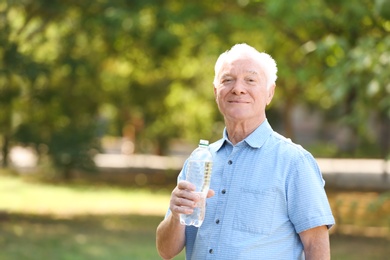 Elderly man with bottle of water outdoors on sunny day