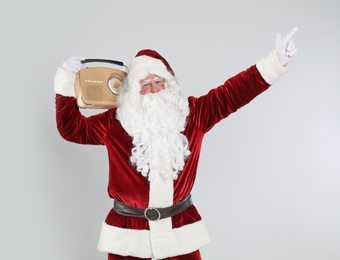 Photo of Santa Claus with vintage radio on light grey background. Christmas music
