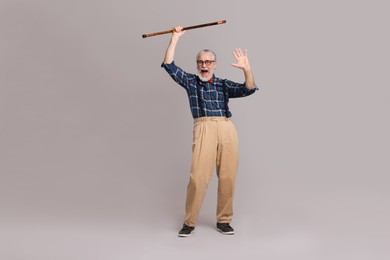 Photo of Cheerful senior man with walking cane on gray background