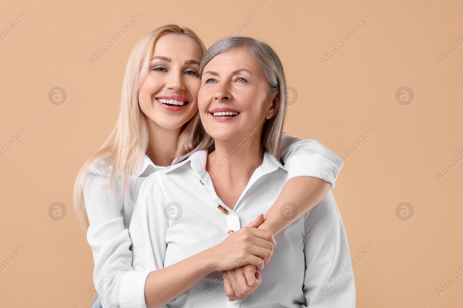 Photo of Family portrait of young woman and her mother on beige background