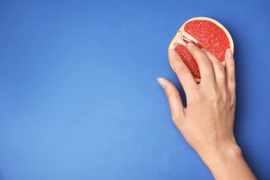 Photo of Young woman touching half of grapefruit on blue background, top view with space for text. Sex concept