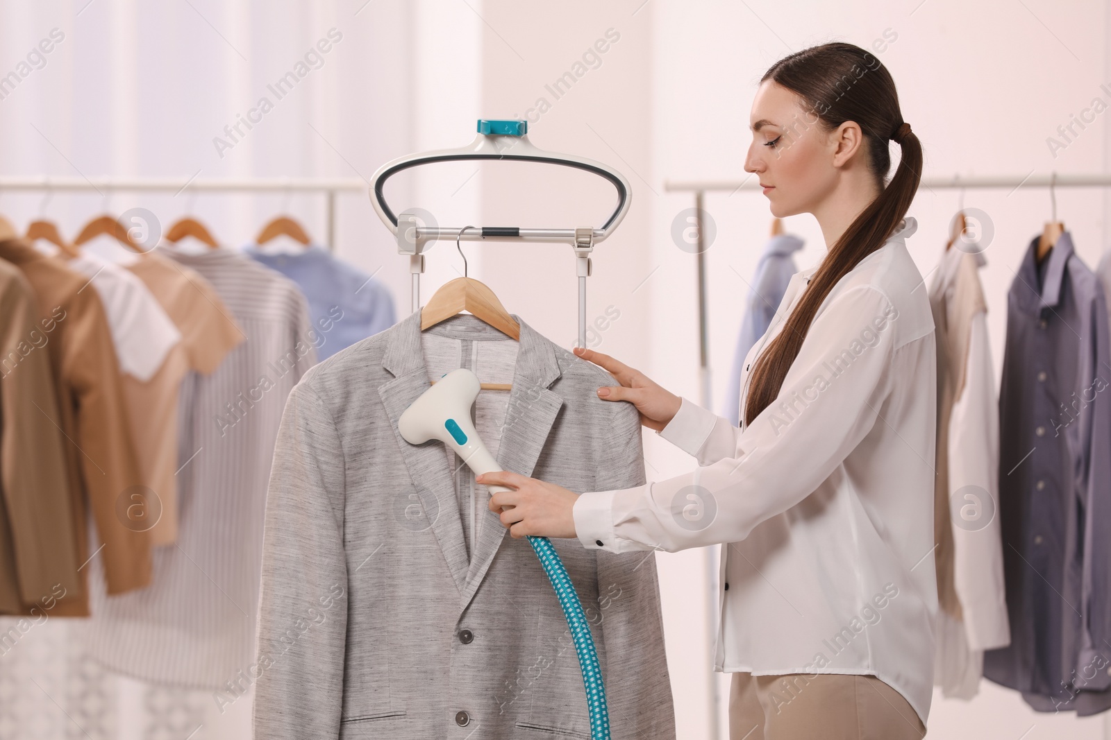 Photo of Woman steaming jacket on hanger in room