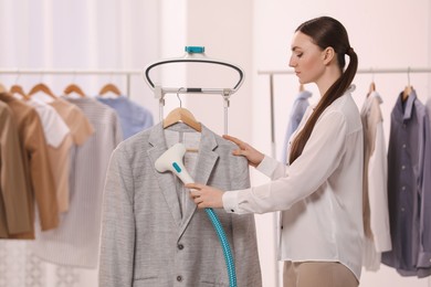 Photo of Woman steaming jacket on hanger in room