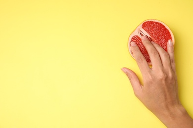 Photo of Young woman touching half of grapefruit on yellow background, top view with space for text. Sex concept