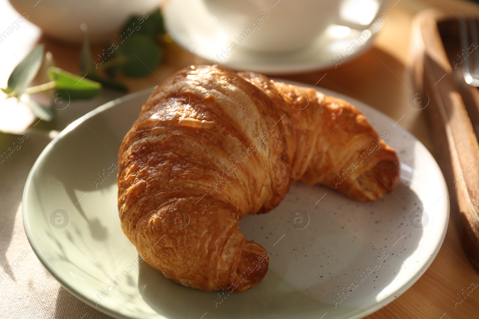 Photo of Tasty croissant served on wooden table, closeup