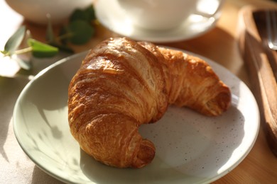 Tasty croissant served on wooden table, closeup