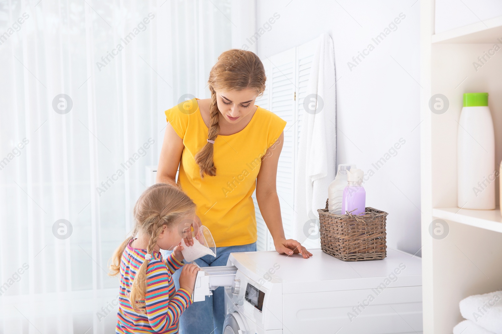 Photo of Little girl helping her mother to do laundry at home