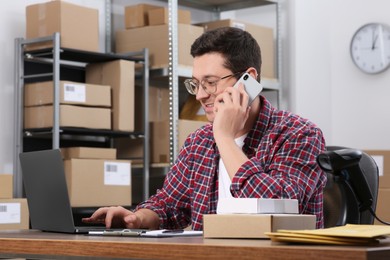 Photo of Seller talking on phone while working in office. Online store