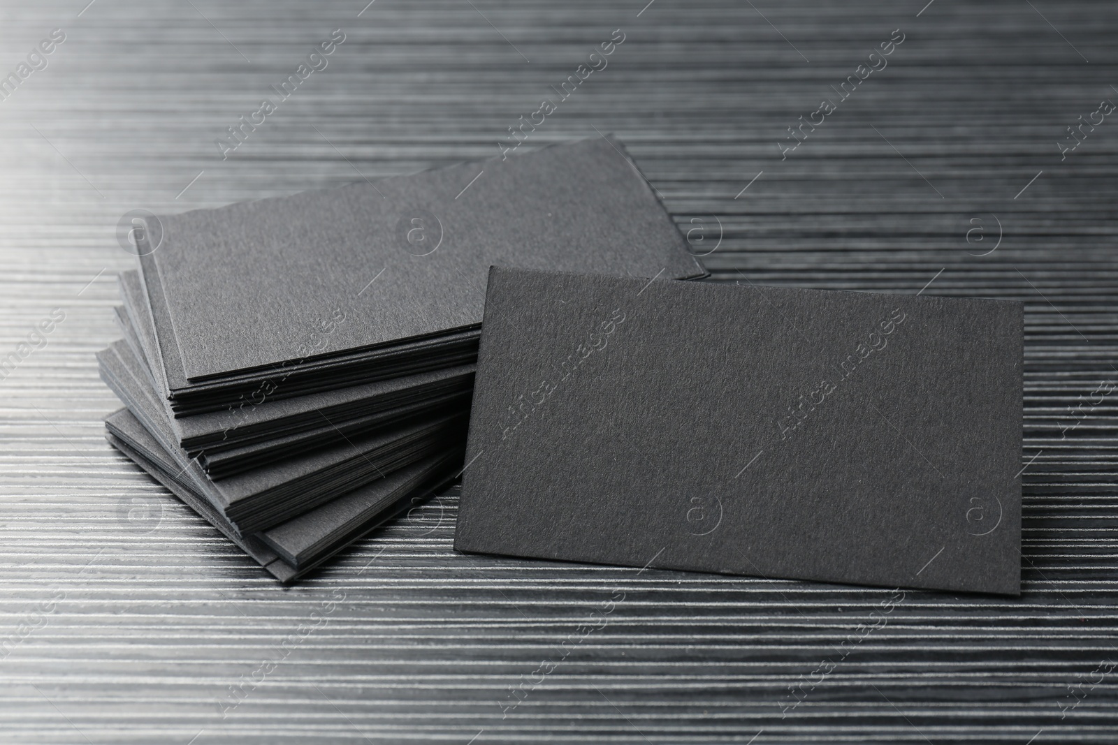 Photo of Blank black business cards on wooden table, closeup. Mockup for design