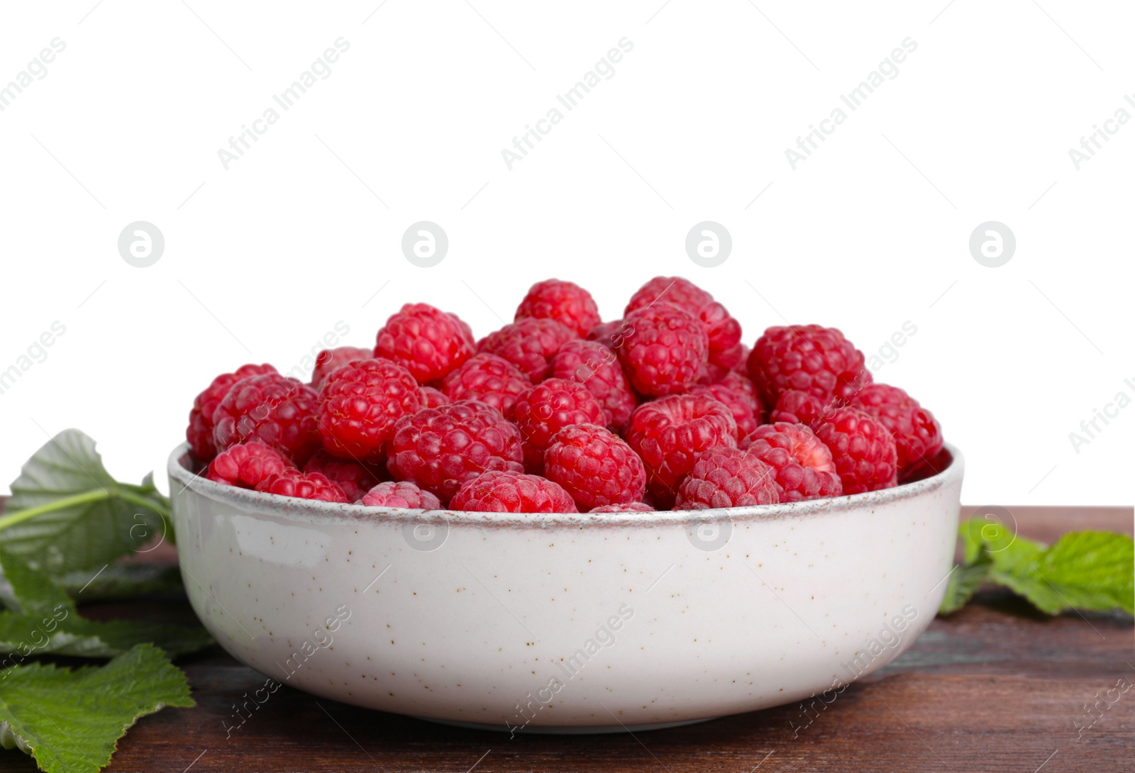 Photo of Bowl of fresh ripe raspberries with green leaves on wooden against white background
